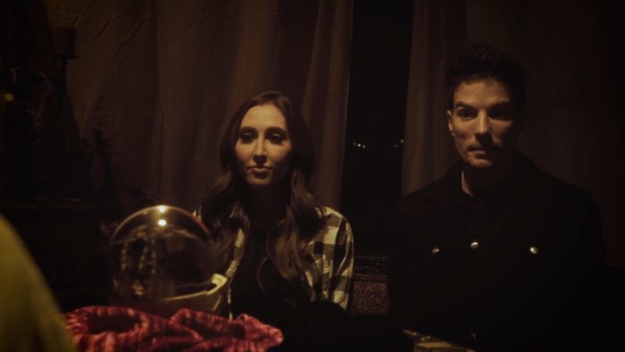 A couple sit in a tent in front of a table with a crystal ball on it in Tales from the Otherside