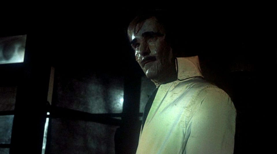 An evil manequin staring away from the camera in a dark, dim room.